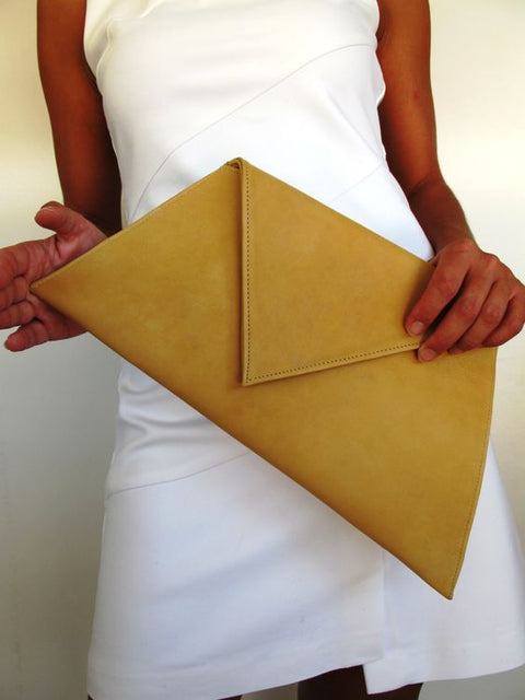 Person in white dress holding mustard yellow geometric flat purse