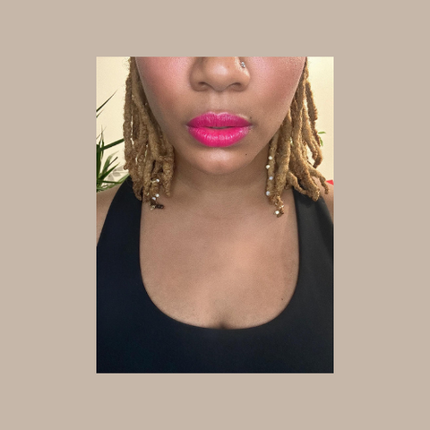 Picture of Black woman's face below eyes with hot pink lipstick on and dreads